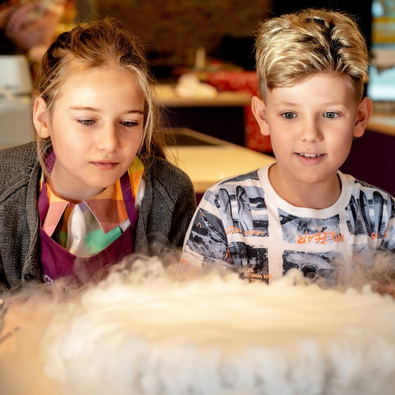 Zwei Kinder beobachten fasziniert ein dampfendes Experiment.